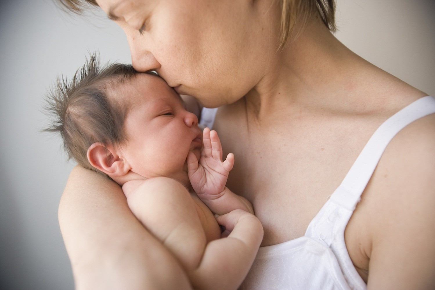 mother kissing new born baby