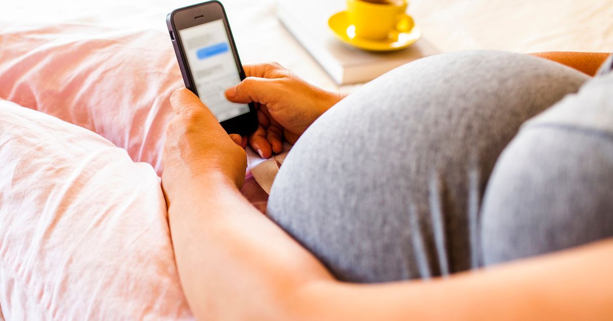 Pregnant woman using phone in bed